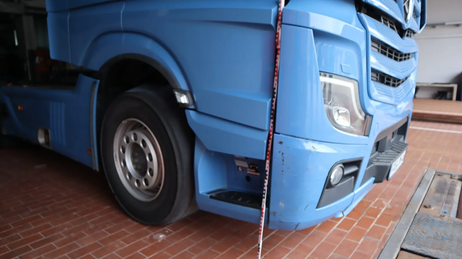 Front eines Lastwagens mit Schaden, daneben ein Messstab.